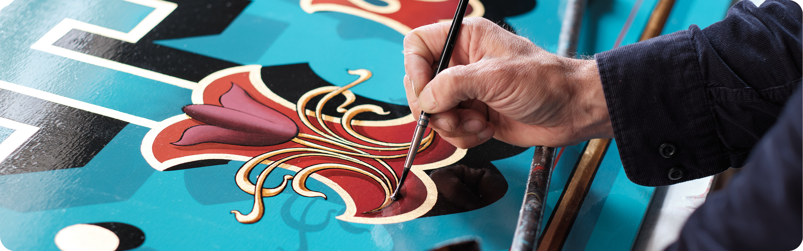 Signwriter at work painting a decorative sign